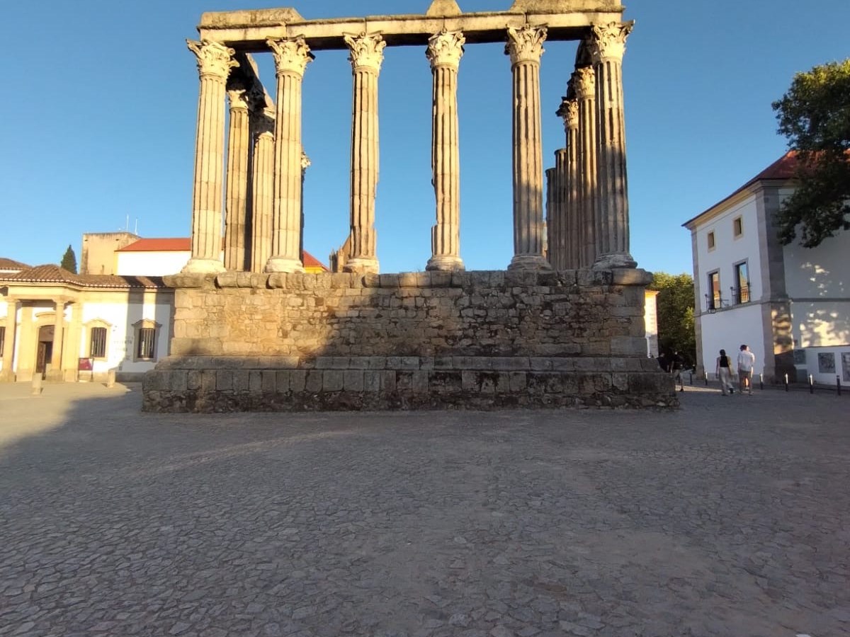 Ancient stone temple with tall columns under clear blue sky.